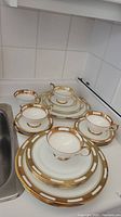 Top-down view of 4 teacups with saucers and a stack of plates, showing general set condition and design