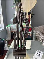 Front view of forged steel statue with four abstract figures on a rectangular base.