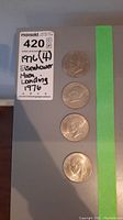 Photo showing four 1976 Eisenhower silver dollar coins in a vertical row with a label indicating the lot details.