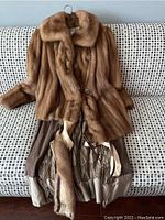 Full coat laid out showing light brown mink fur exterior and inner lining with visible tears.