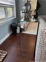 Full side view of the mirrored plant stand against wall, showing reflective mirrored panels and tagged with lot number.