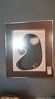 Framed abstract print showing organic shapes in shades of gray and black with white highlights, signed and numbered but slipped inside frame.