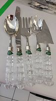 Five-piece serving set with stainless steel heads and clear Shannon Irish Crystal handles with green label stickers.