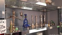 Shelving display showing blue glass decanter with silver overlay, silver plate candelabras, and salt & pepper shakers.
