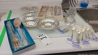 Wide overview of all items laid out on countertop including salt cellars, flatware, servers and dishes