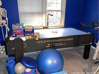 Full side view of Gold Standard Games air hockey table in room with exercise balls and board games.