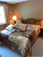 Full view of made bed with mattress, pillows, decorative bedspread, and nightstands showing bed setup