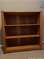 Front view of wooden bookcase showing three shelves and wood grain pattern.