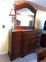 Front view of the wood dresser with attached mirror, showing ten drawers and central cabinet with metal handles.