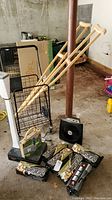 Photo showing 6 Duraflame logs in packaging, black wire rolling shopping cart, white Health-O-Meter standing scale, Vornado space heater fan, wooden crutches leaning on pole, novelty box purse on floor near logs.