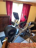 Side view of Cybex Arc Trainer showing frame, flywheel housing, handles, and console.