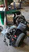 Full view of the folding golf cart, bats, rug, backpack, and Mickey Mantle photo grouped together on the floor.