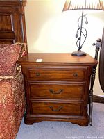 Front view of the wood night stand showing three drawers with metal hardware and a polished finish.