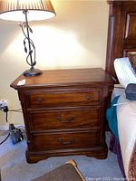 Front view of the wood nightstand with three drawers, showing metal handles and a smooth polished finish.