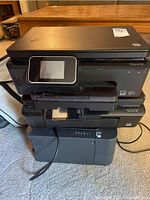 Stacked view of the three printers showing HP Photosmart models and Brother laser printer with cables, showcasing physical condition and model stickers.