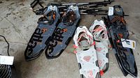 Three pairs of snowshoes with attached bindings and cleats, including two pairs of Atlas Trail 930 and one pair of Atlas Elektra Trail 23, shown with several trekking poles.