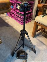 Adjustable metal and plastic tripod with black Minolta branded camera case beneath it.