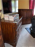 Two piece set: wood armoire cabinet with two doors and three drawer chest with books and television on top, showing general build and finish.