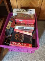 Purple crate containing assorted chess books, boxed Chronos digital game clock, and stacked Sega Genesis game boxes