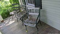 Three antique metal frame patio chairs with wooden slat seats on a porch, showing paint chipping and wear.
