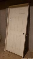 Front view of white door leaning with door frame visible.