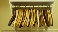 Wooden clothing hangers on rod, displaying various shades and some wear.