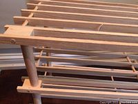 Close-up photo of the wooden three shelf shoe rack showing slatted wood shelves and rounded dowel supports.