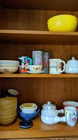 Shelf with mugs, bowls, sugar dish, and cups showing assortment of kitchen and tableware items including fine china teacup and mugs