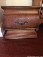 Front view of side table showing curved drawer front and decorative metal handle.