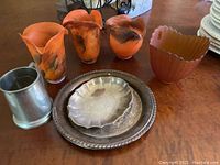 Photo showing eight items: three amber glass vases or sconces, one amber glass wide scalloped vase, two large silverplate dishes, one smaller silverplate octagonal dish, and a pewter tankard.