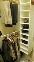 Photo showing rack with hanging dress slacks and shelves with dress shoes and hats.