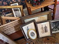 Various framed wall art pieces and basket on floor, some framed with glass, assorted sizes and styles