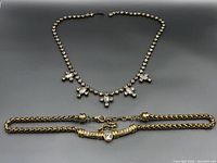 Two gold tone necklaces shown side by side. Rhinestone necklace has multiple clear stones and is marked Made in Austria. Gold chain necklace has double chain design with a central clear stone detail.
