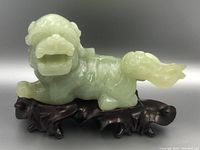 Front-left view of the pale green jade foo dog on its wooden stand