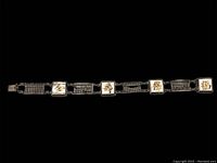 Full view of silver bracelet laid flat showing alternating mother of pearl panels with Chinese characters and abacus designs.