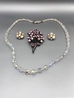 Full view of the necklace, brooch and earrings on gray background showing overall condition and colors