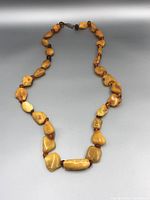 Full view of the necklace laid flat with visible egg yolk and cognac amber beads