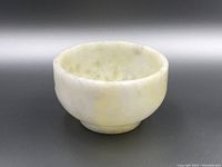 Side view of small round jade bowl showing smooth surface and subtle color variation