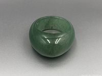Photo from the front-left angle showing the ring's smooth polish and green color with natural variations in the jade.