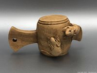 Side angle of beige-colored Japanese netsuke showing carved frogs and the flat tang with hole for stringing.