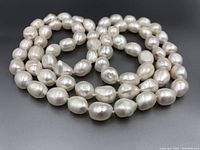 Single strand pearl necklace with large, irregularly shaped baroque pearls on a black background.