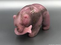Front left angle of the polished rhodonite grizzly bear holding a fish in its mouth, showing color and detail.