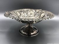 Side view showing the pedestal base and openwork bowl with ornate edge.