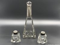 Front view of salt and pepper shakers flanking a taller crystal vinegar bottle with sterling silver top.