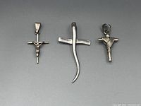 Three sterling silver cross pendants displayed side by side showing their distinct styles