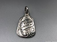 Front view of the silver pendant showing intricate First Nations style engraving