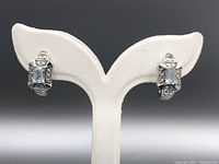 Pair of topaz earrings displayed on white stand showing front view of the gems and setting.