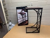 Side view of side sofa table showing leaf design metal support panel and wooden top.