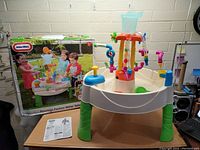 Front angle showing Fountain Factory Water Table with box and instruction manual, funnel on top with visible damage but intact setup.