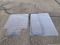 Photo of two clear floor protector chair mats side by side on pavement, one designed for carpet with a textured underside and cut-out section, the other for hard floors with a smooth underside